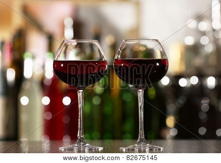 Two glasses of wine with bar on background