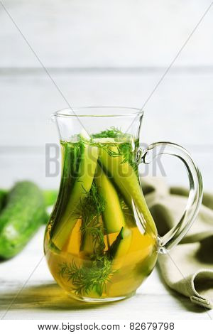 Glass ewer with fresh organic cucumber water on wooden table