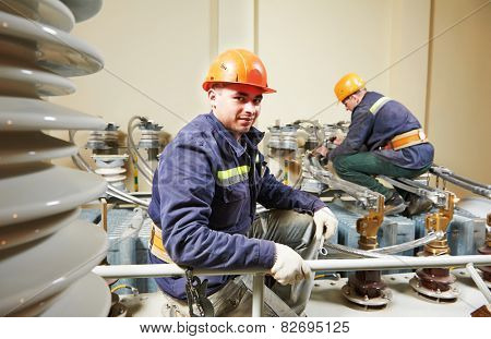 Electricians lineman repairman worker at huge power industrial transformer installation work