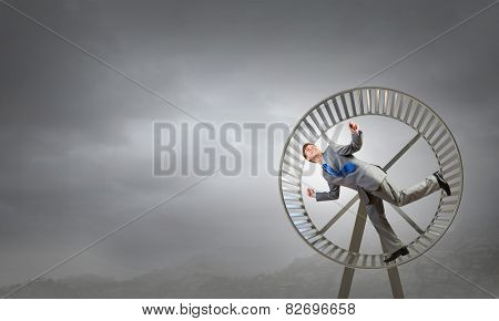 Young businessman running in huge hamster wheel