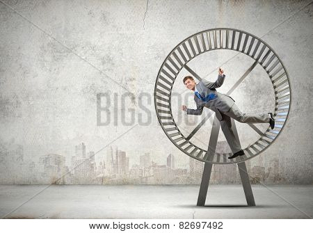 Young businessman running in huge hamster wheel