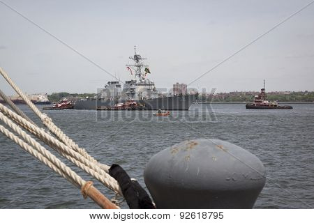 STATEN ISLAND, NY - MAY 20 2015: USS Barry (DDG 52) is guided into port by McAllister tugboats at Sullivans Pier, with a mooring bollard in the foreground at the beginning of Fleet Week.