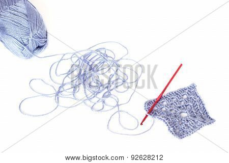Light Blue Skein Of Acrylic Thread With The Unwound String, Square Crochet Element And Red Hook