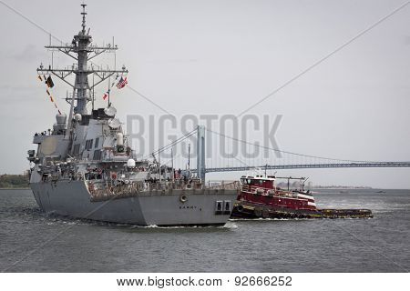 STATEN ISLAND, NY - MAY 20, 2015: USS Barry (DDG 52) is guided into port near the Verrazano-Narrows Bridge by McAllister tugboats at Sullivans Pier after the Parade of Ships that starts Fleet Week.