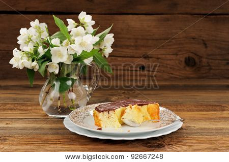 Homemade Baked Pudding With Chololate Icing And Jasmine Flowers On Wooden Background
