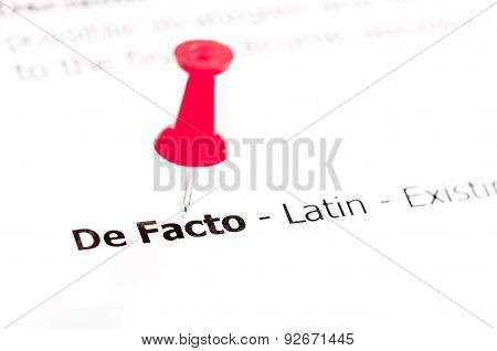 Words De Facto Pinned On White Paper With Red Pushpin
