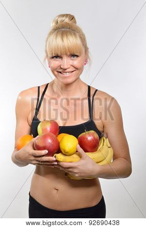 Attractive happy middle-age fit woman holding fruit and vegetables. Healthy eating, fitness, diet, vegetarianism and rawfoodist concept.