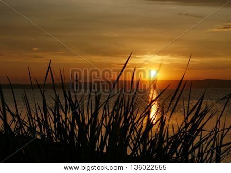 Late summer evening on the lake. The sun sets behind the horizon.