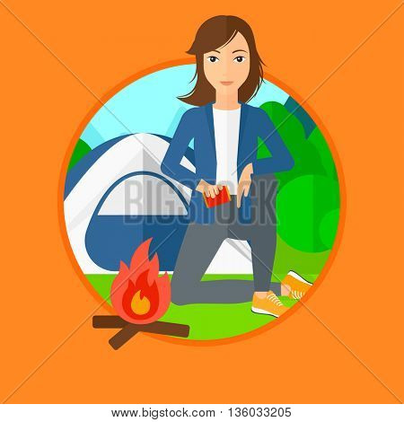 Woman kindling campfire on the background of camping site with tent. Tourist relaxing near campfire. Woman sitting near campfire. Vector flat design illustration in the circle isolated on background.