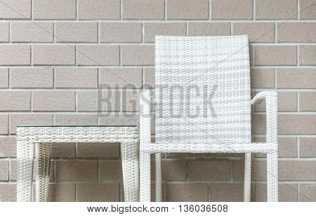 Closeup wood weave table and wood weave chair on blurred brown brick wall texture background beautiful interior in relaxation of house concept