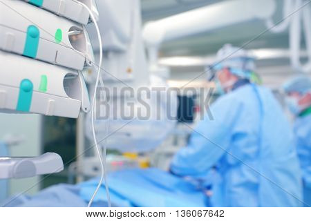 Medical lines with a drug against the background of surgeons in cathlab.