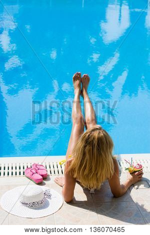 woman in a hat enjoying cocktail in a swimming pool