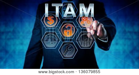 Business person is touching ITAM on an interactive virtual control monitor. Business strategic metaphor information technology concept corporate terminology and acronym for IT Asset Management.