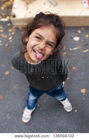 ZAGREB, CROATIA - OCTOBER 14, 2013: Portrait of cute Roma girl  sticking out tongue for camera at garbage dump.