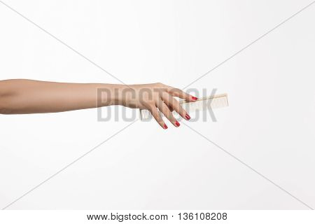 Rake comb isolated on white background. Woman's hand holding rake comb in studio ocer white. Hairdressing and saloon concepts.