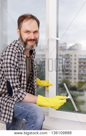 Mature man cleaning windows using squeegee