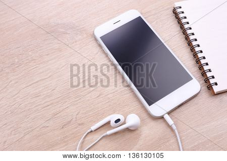 smartphone mockup with earphone and papre note on wooden background