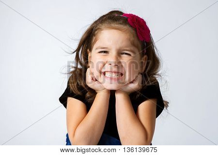 Adorable and expressive girl gritting her teeth and scrunching her face in a silly grin.