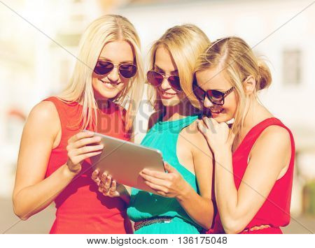 holidays and tourism concept - beautiful blonde girls toursits looking into tablet pc in the city