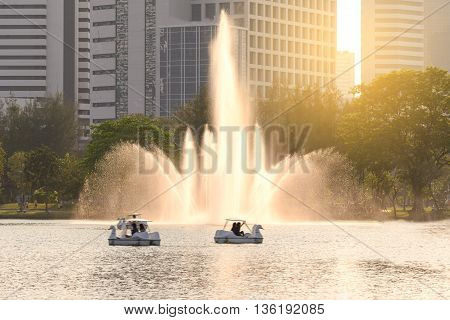 Beautiful fountain in urban lake with closeup building background.