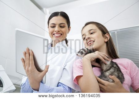 Doctor Using Digital Tablet While Girl Holding Weasel