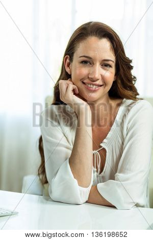 Portrait of businesswoman with hand on chin at desk in office