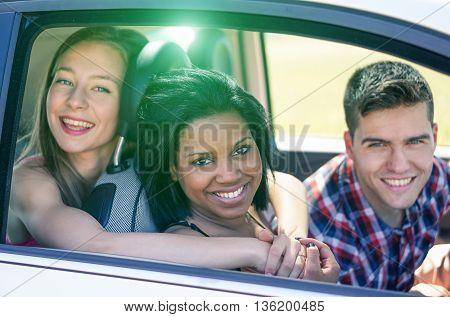 Multiracial friends driving to vacation in the car - Happy mixed race in an automobile with back lighting - Multi ethnic friendship concept - Soft focus on black girls with soft warm filter
