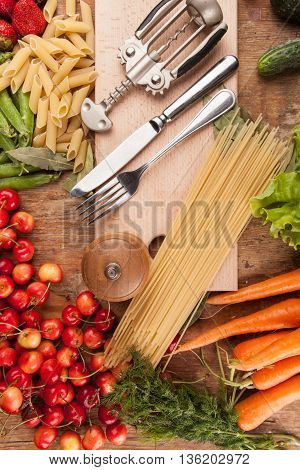 Italian food background, with vine tomatoes, basil, spaghetti, mushrooms, olives, parmesan, olive oil, garlic, peppercorns, rosemary, parsley and thyme. Slate background.