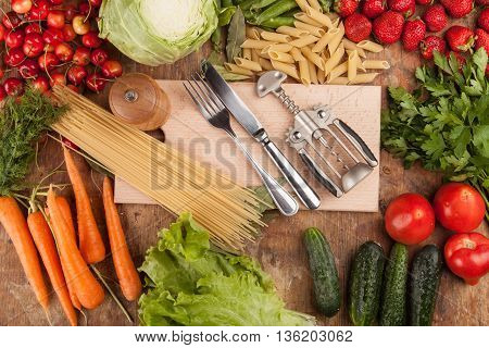 Italian food background, with vine tomatoes, basil, spaghetti, mushrooms, olives, parmesan, olive oil, garlic, peppercorns, rosemary, parsley and thyme. Slate background.