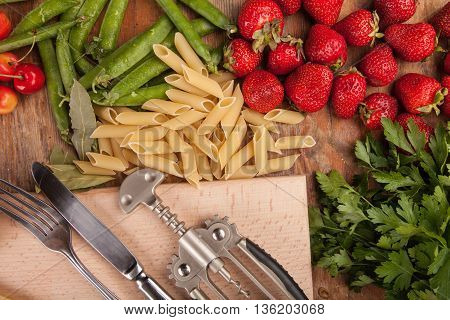 Italian food background, with vine tomatoes, basil, spaghetti, mushrooms, olives, parmesan, olive oil, garlic, peppercorns, rosemary, parsley and thyme. Slate background.