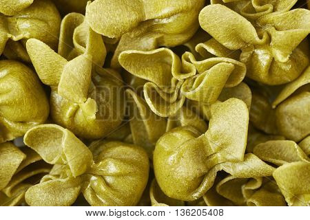Surface covered with sacchettoni green stuffed sacchetti pasta, close-up fragment crop as a background composition