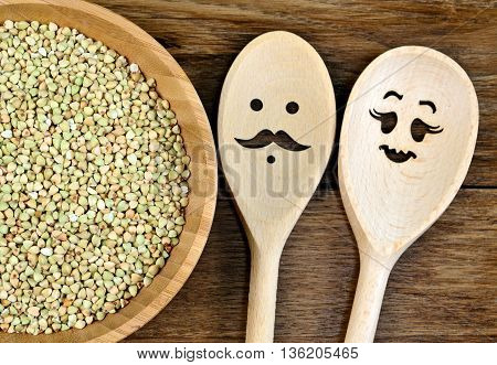 Green buckwheat in bowl and lovely wooden spoon