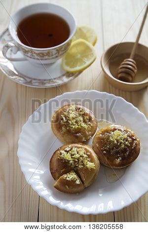 Three lemon cakes with a cup of tea and a plate of honey