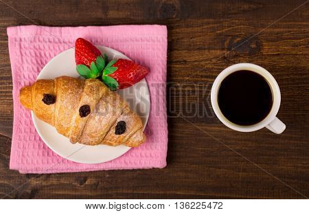 delicious golden croissants filled with strawberry marmalade and coffee. wooden table background. Top view