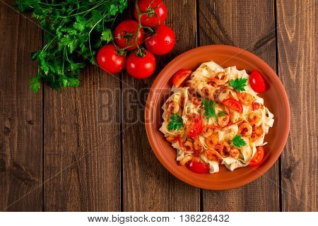 Fettuccine pasta with shrimp tomatoes and herbs. wooden background. Top view