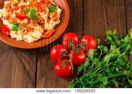 Fettuccine pasta with shrimp tomatoes and herbs. wooden background. Top view