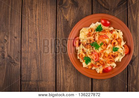 Fettuccine pasta with shrimp tomatoes and herbs. wooden background. Top view