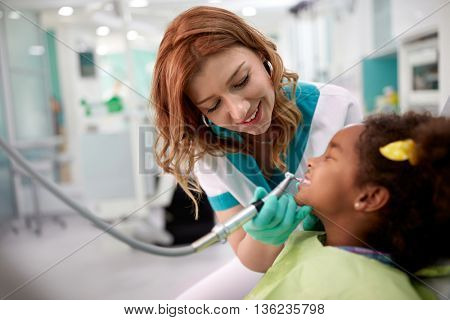Child as patient with female dentist during dental intervention in dental clinic 