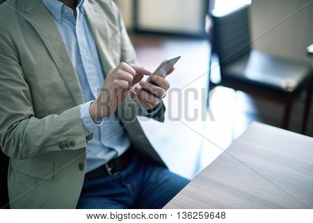 Handsome man working with smartphone and documents at cafe