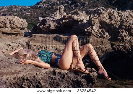 Beautiful sensual blonde in a greek sandals at the seashore. Summer travel fashion photo