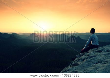 Man Sit On Peak. Colorful Mist And Fog In Forest Valley Bellow.