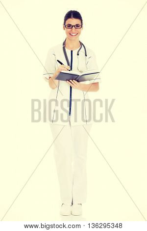 Young female doctor wirting in a book.