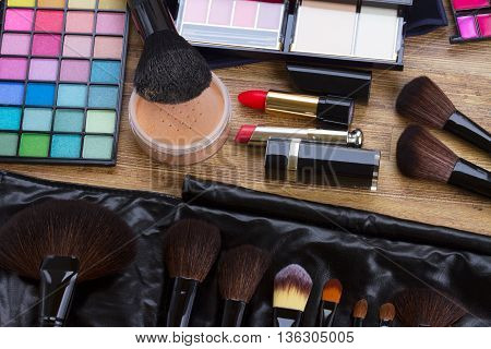 Set of professional make up brushes, lipsticks, maskara, eye shadows and powder on desktop, top view
