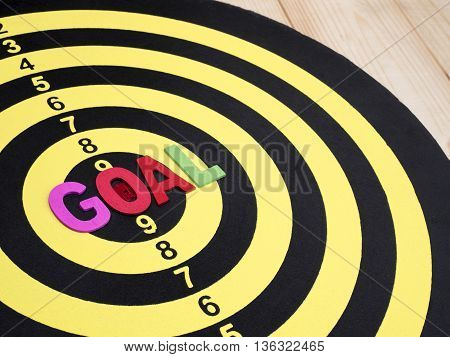 Close up word spell GOAL on dart board with wood background (Selective focus)