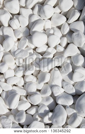 Background of white pebbles of different factions under tight sunlight