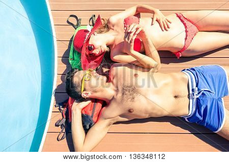 Young couple sun tanning at pool deck of cruise ship - Beautiful lovers holding hands lying on yacht poolside - Concept of unforgettable love moment on the honeymoon vacation - Soft vintage filter