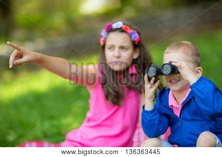 Boy and girl exploring the environment with a binocular