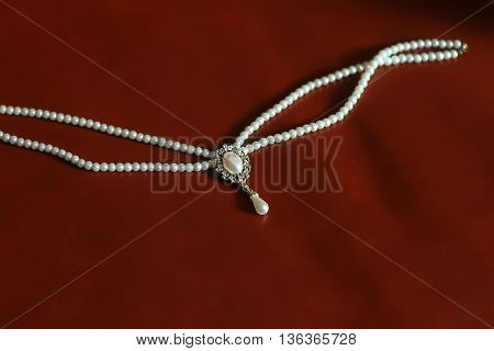 Elegant pearl necklace strands of precious white beads on brown silk background