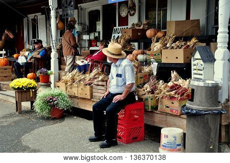 Bird-in-Hand Pennsylvania - October 14 2015: Mennonite horse & buggy driver sitting by the front porch of the Old Village Hardware Store waiting for clients