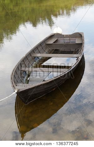 Rural wooden rowboat partly filled with water. No people